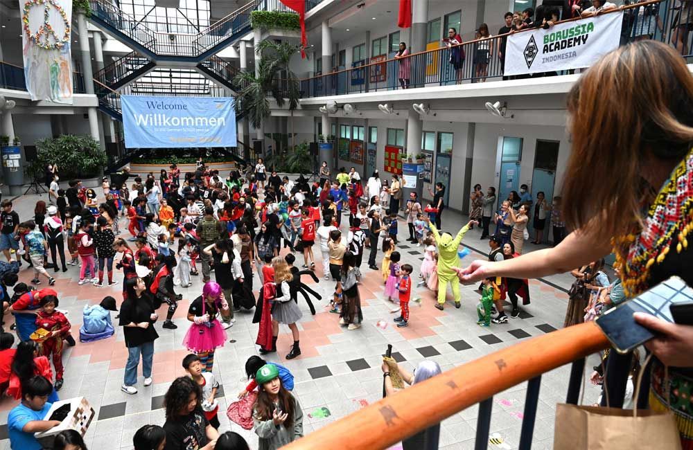 A woman is standing on a balcony overlooking a large group of people dressed in costumes.