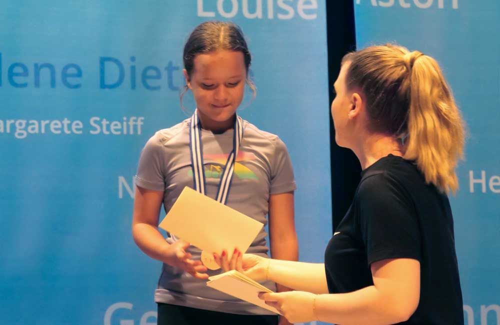 A woman is giving a medal to a young girl