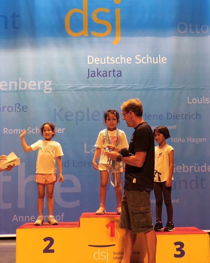 A group of children standing on a podium that says dsj