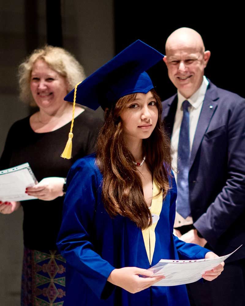 A woman in a graduation cap and gown is holding a certificate