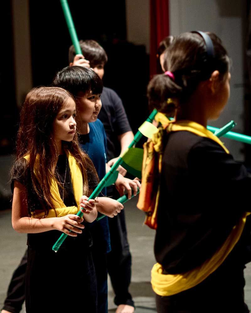 A group of children are holding green sticks in their hands.