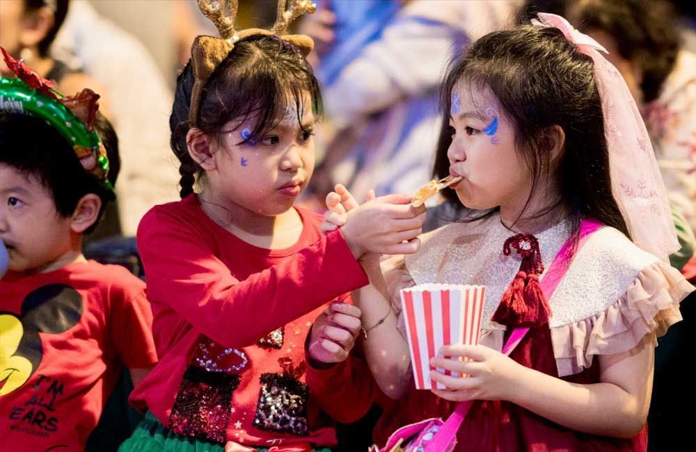 A group of children are sitting in a room eating popcorn.