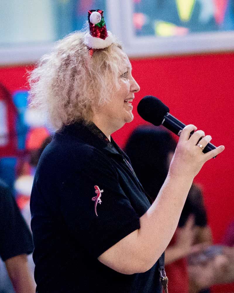 A woman wearing a santa hat is holding a microphone
