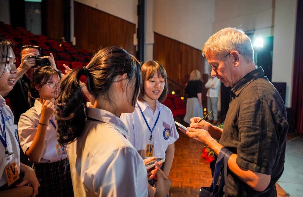 A man is talking to a group of young girls in a room.
