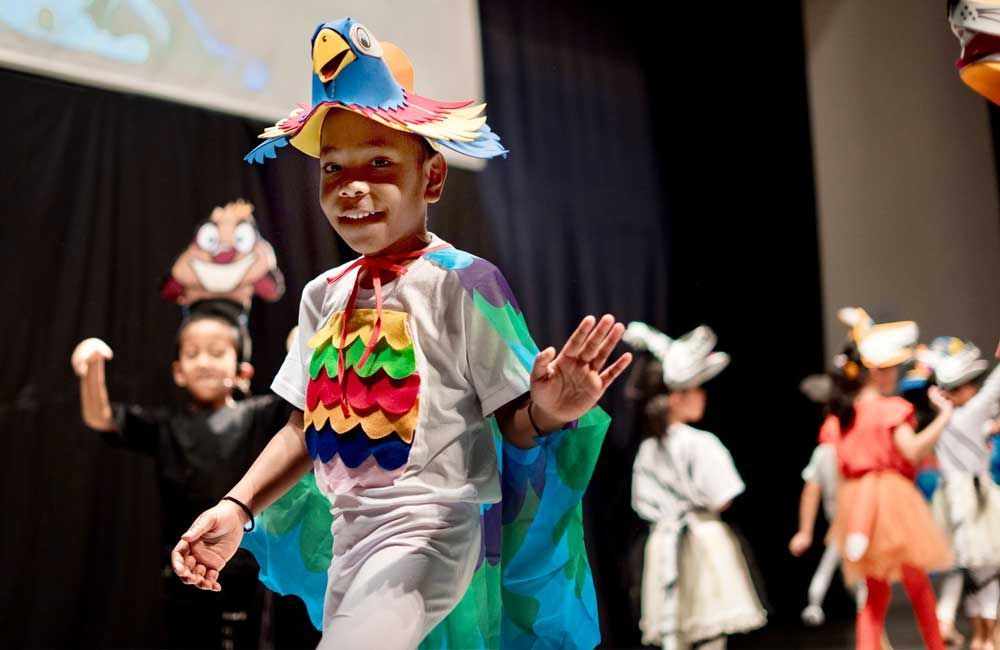 A group of children dressed in costumes are dancing on a stage.