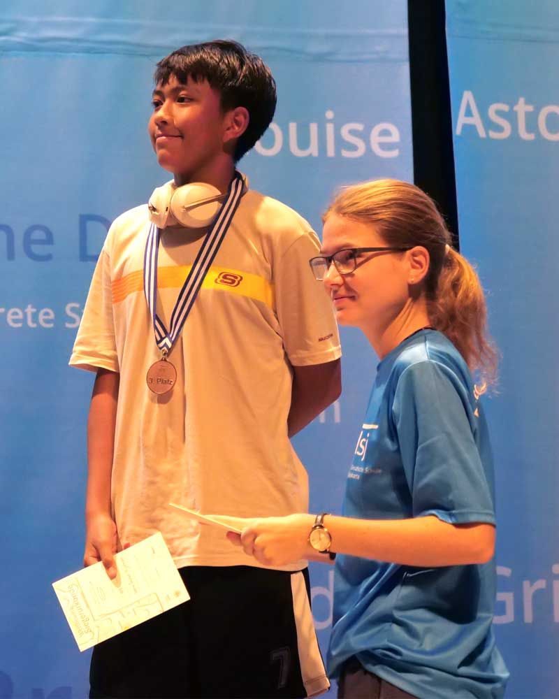 A boy with a medal around his neck stands next to a girl