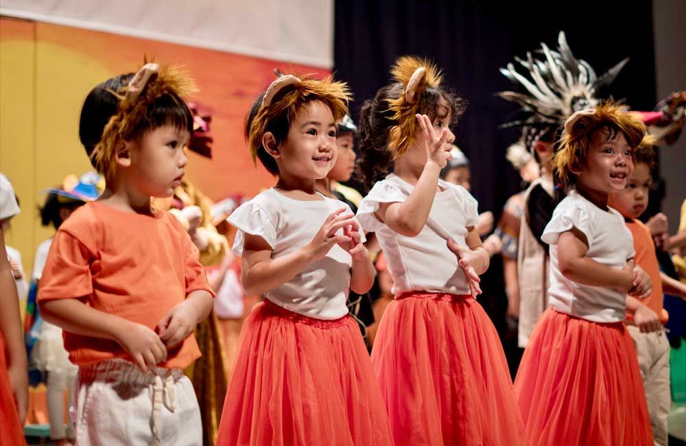 A group of young children are dancing on a stage.