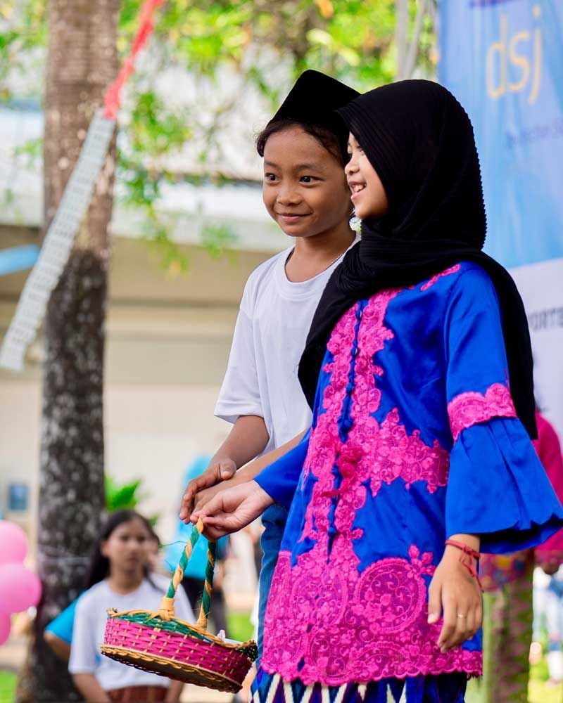 A boy and a girl are standing next to each other in front of a sign that says dsi
