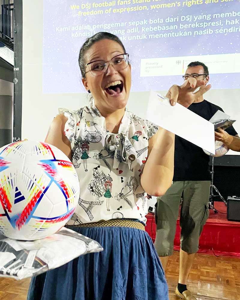 A woman is holding a soccer ball and a piece of paper.