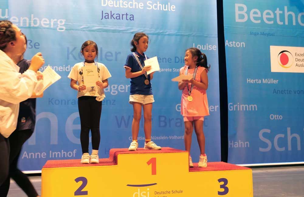 Three young girls standing on a podium with the number 1 on it