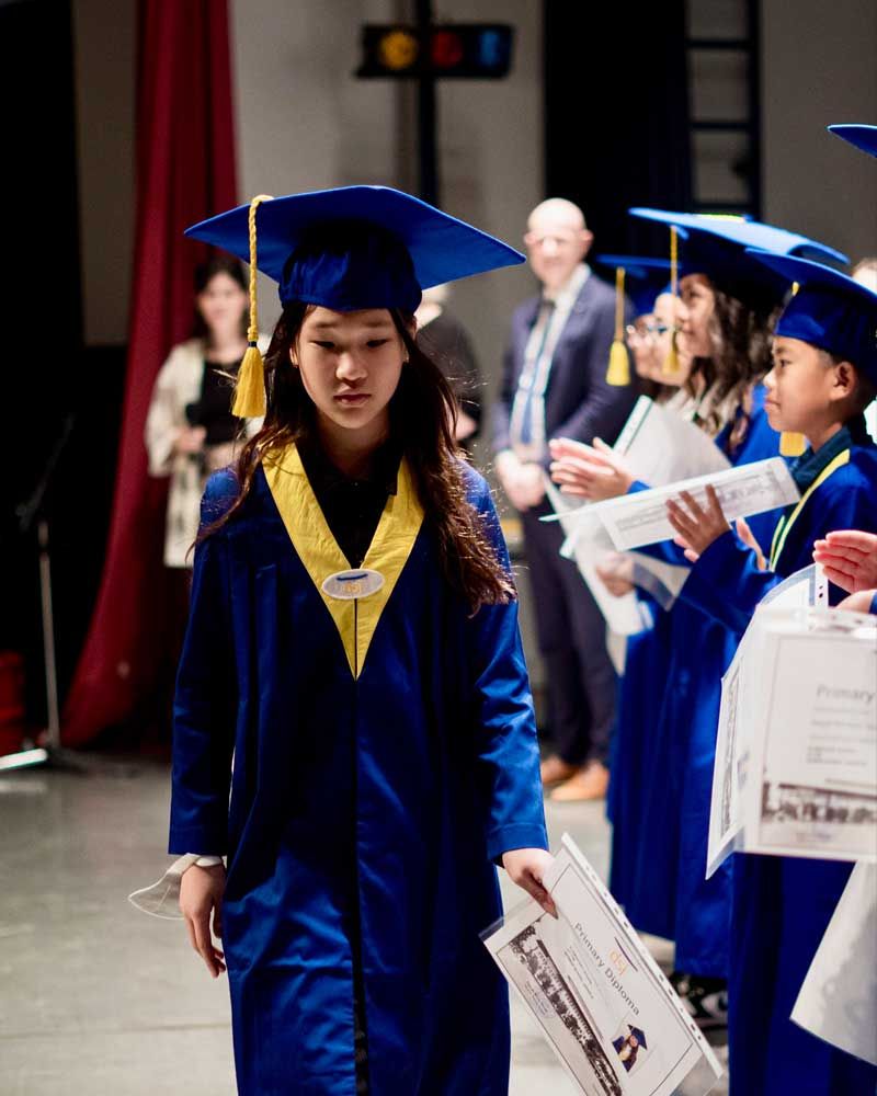 A girl in a graduation cap and gown is holding a diploma