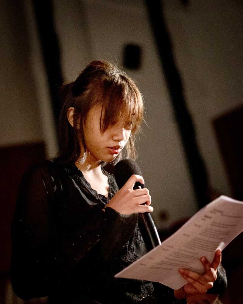 A woman is holding a microphone and reading a piece of paper