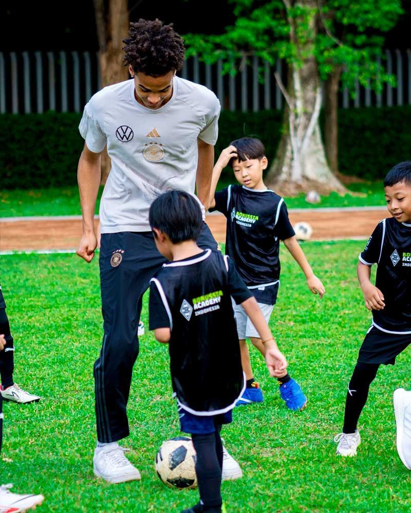 A man is teaching a group of young boys how to play soccer.