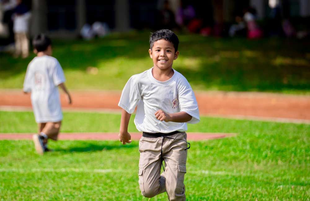 A young boy is running on a lush green field.