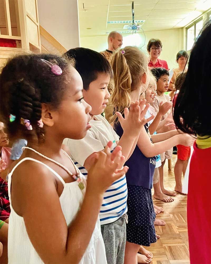 A group of children are clapping their hands in a room.
