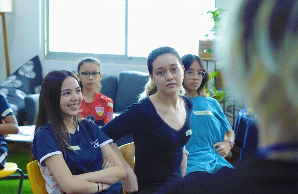 A group of young women are sitting in a classroom.
