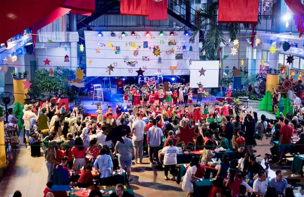 A large group of people are gathered in a large room at a christmas party.