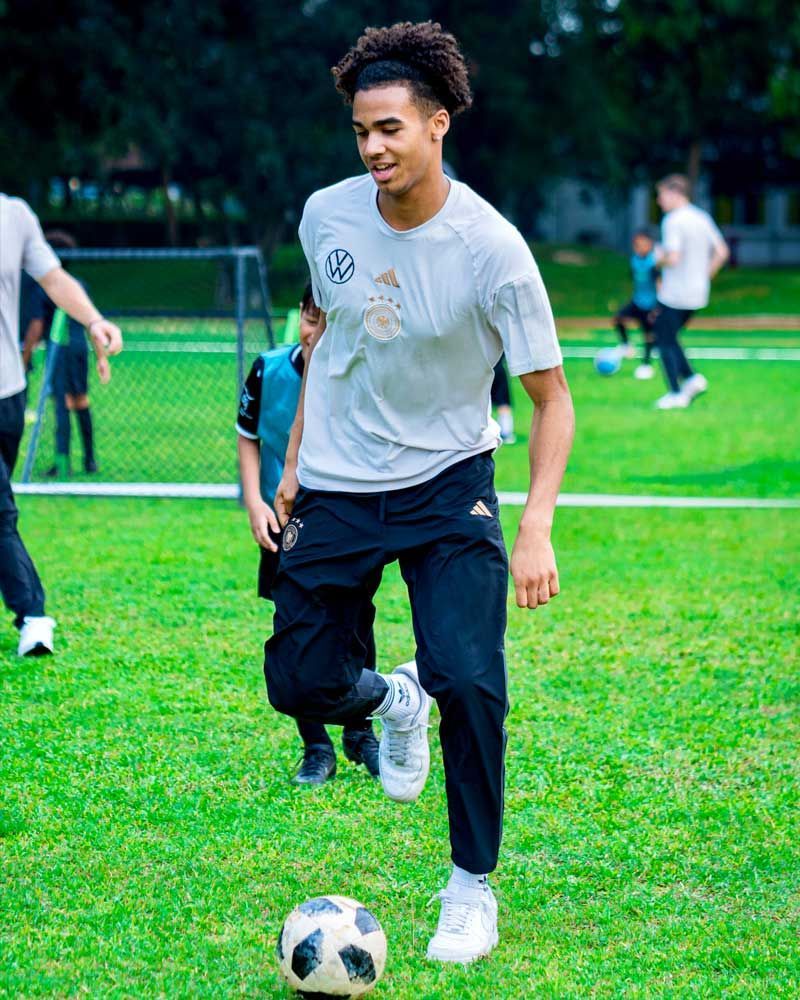 A young man is kicking a soccer ball on a field.