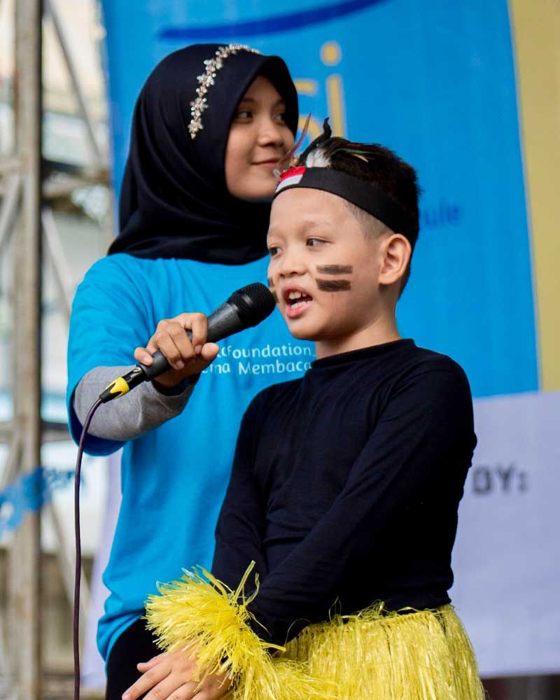 A woman is singing into a microphone next to a young boy