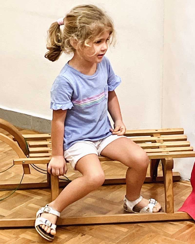 A little girl is sitting on a wooden bench.