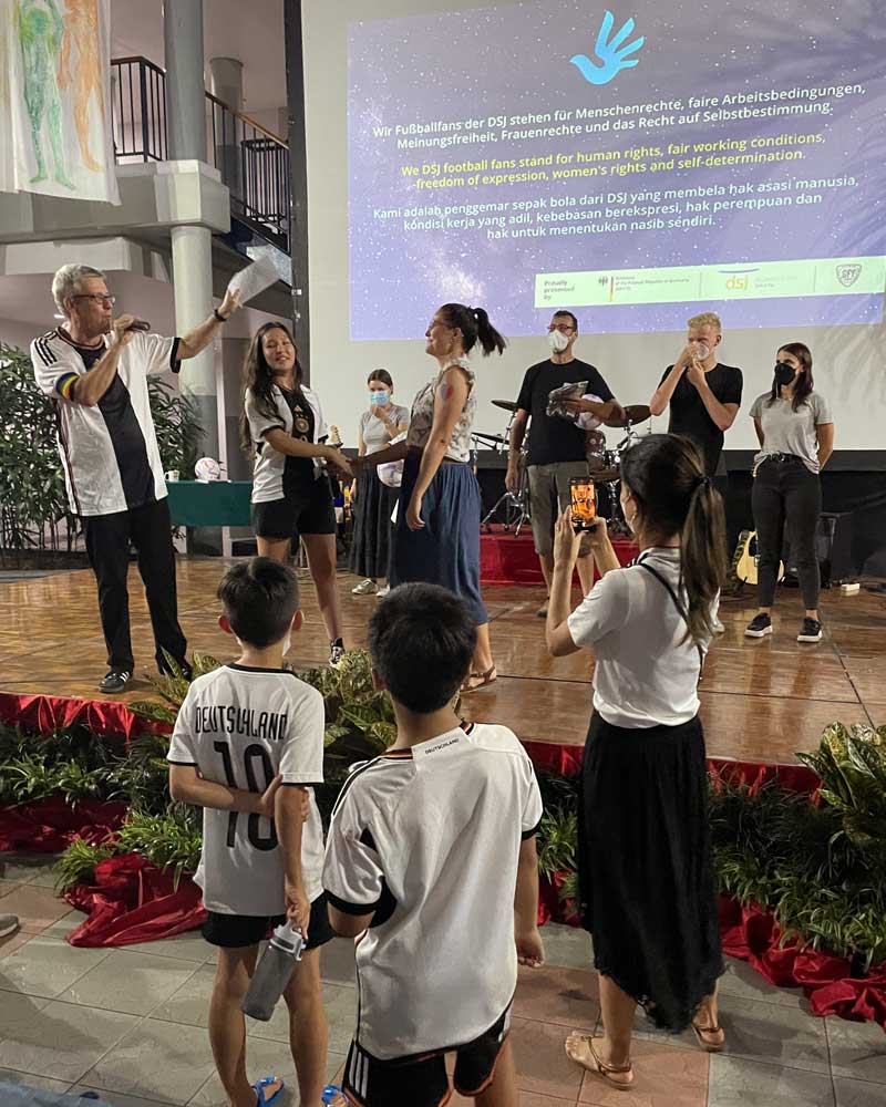 A group of people are standing on a stage in front of a large screen.