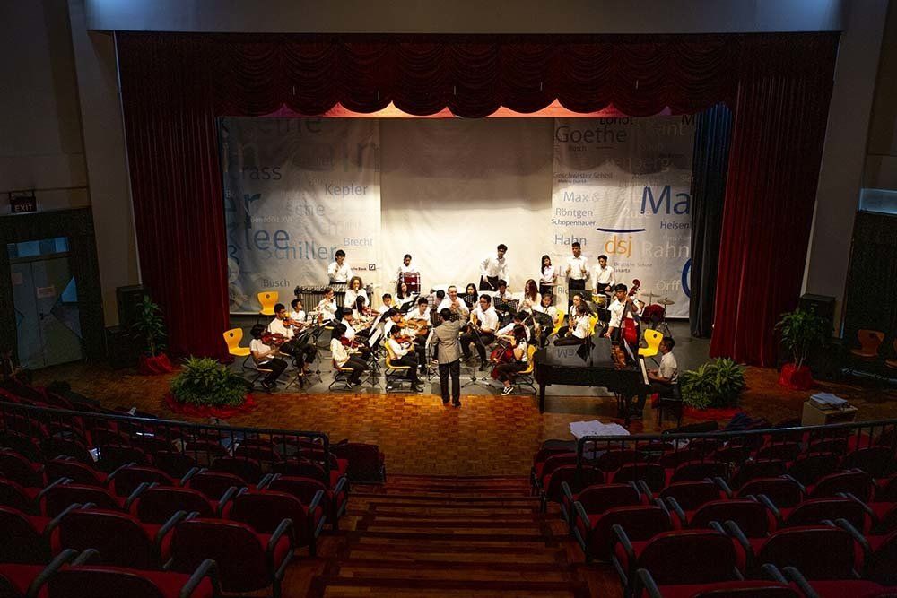 A large orchestra is playing on a stage in an auditorium.