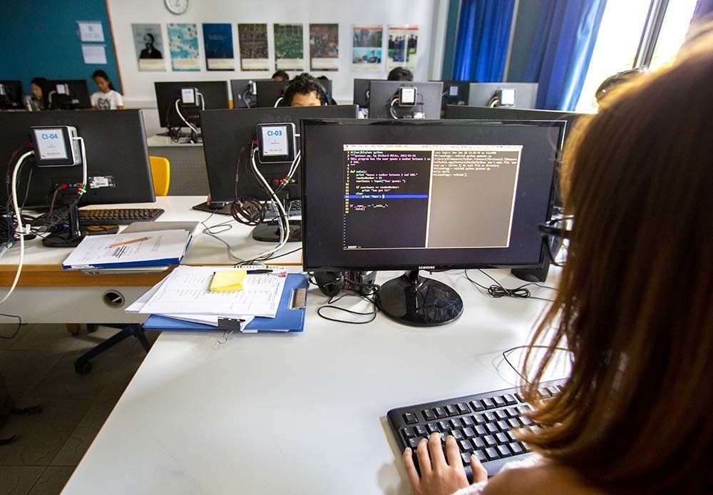 A woman is typing on a keyboard in front of a computer monitor.