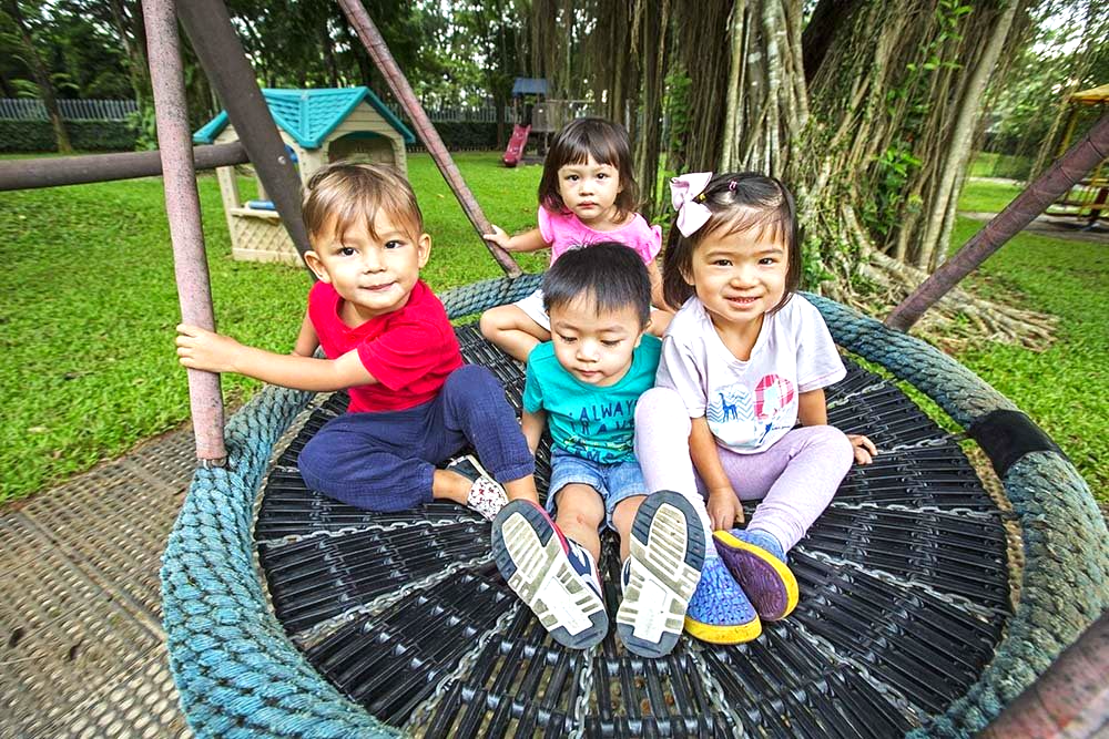 A group of children are sitting on a tire swing in a park.