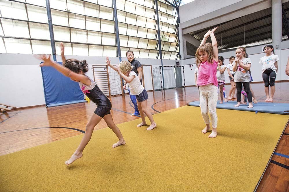 A group of young girls are doing exercises on a mat in a gym.