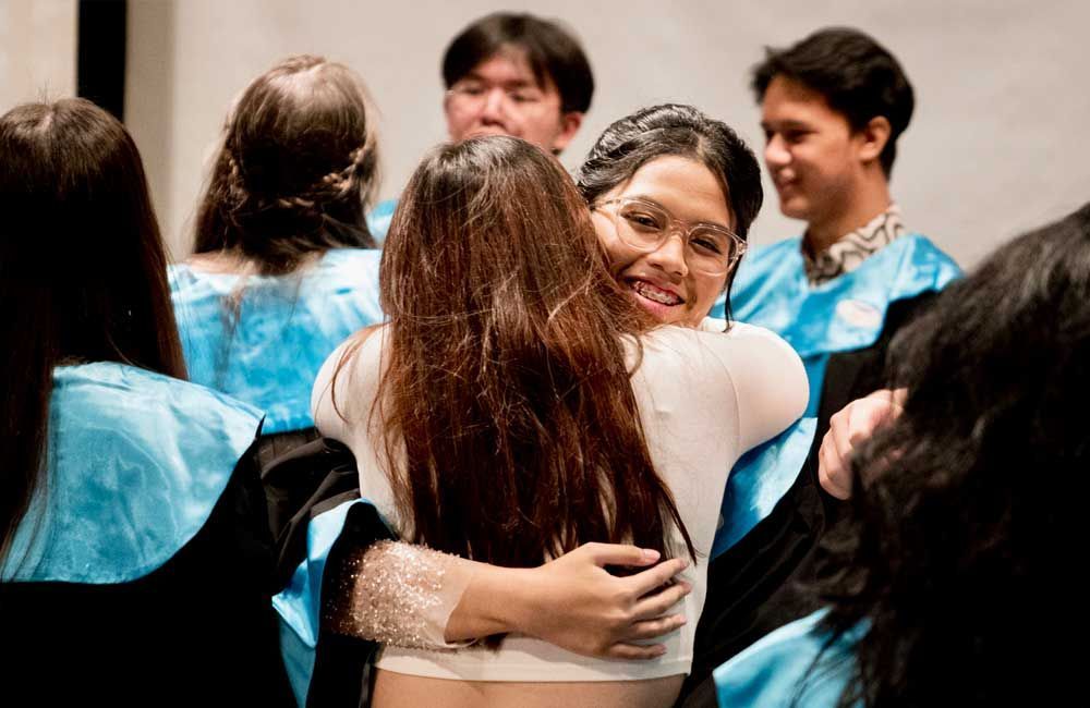 A group of people are hugging each other at a graduation ceremony.