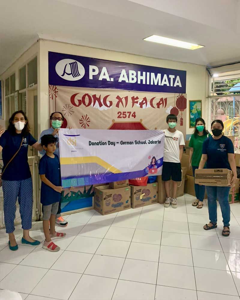 A group of people standing in front of a sign that says pa abhimata