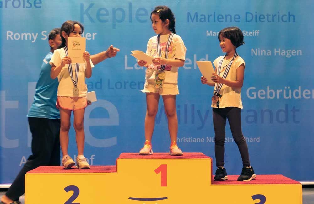 A group of young girls standing on a podium with the number 1 on it