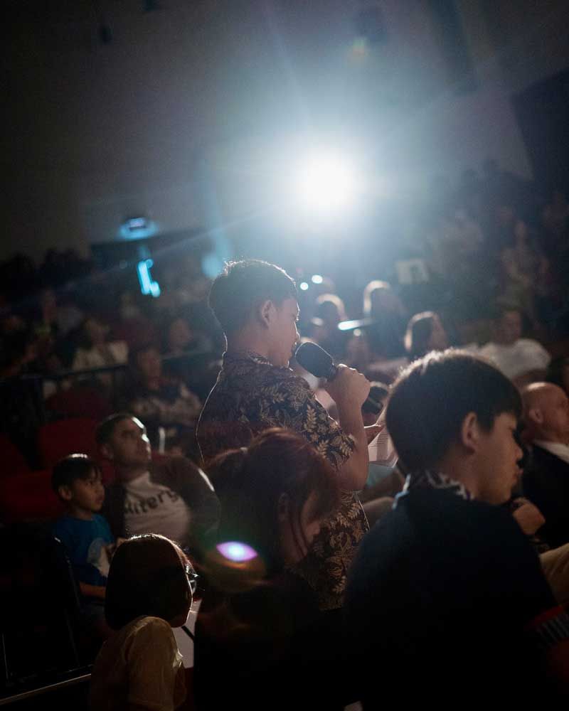 A group of people are sitting in a dark room watching a movie.
