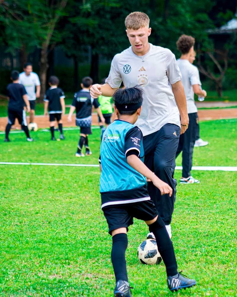 A man is teaching a young boy how to play soccer on a field.