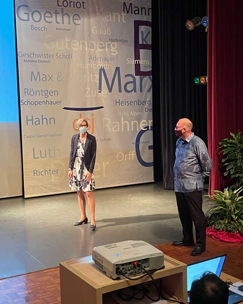 A man and a woman are standing on a stage in front of a projector.