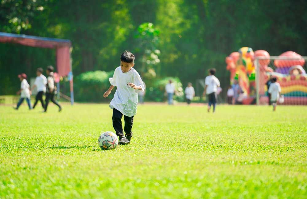 A young boy is kicking a soccer ball on a field.