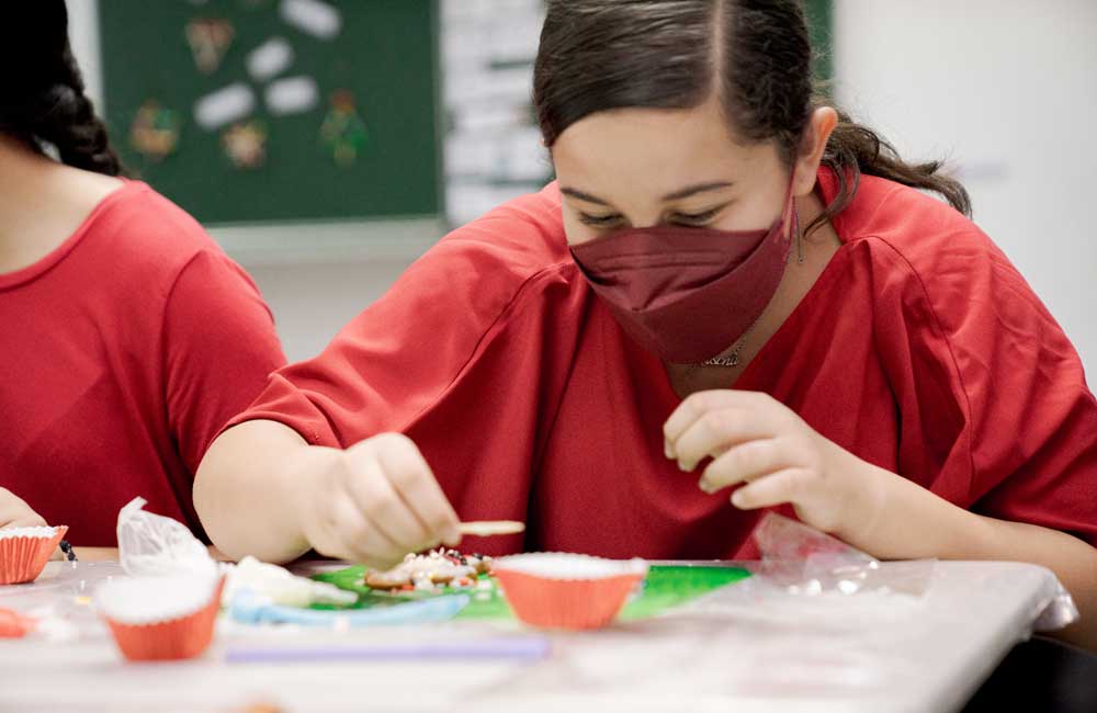 A girl wearing a mask is sitting at a table.