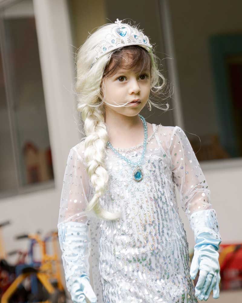 A little girl dressed as elsa from frozen wearing a wig and gloves.