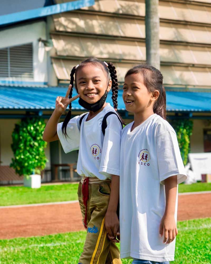 Two young girls are standing next to each other on a field.