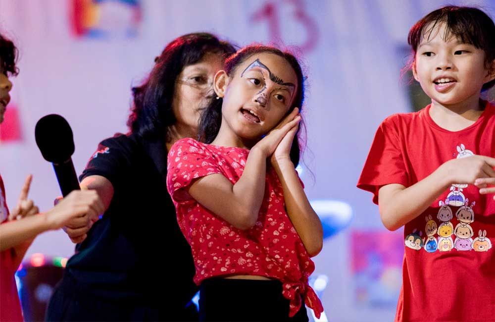A group of young girls are standing in front of a microphone on a stage.
