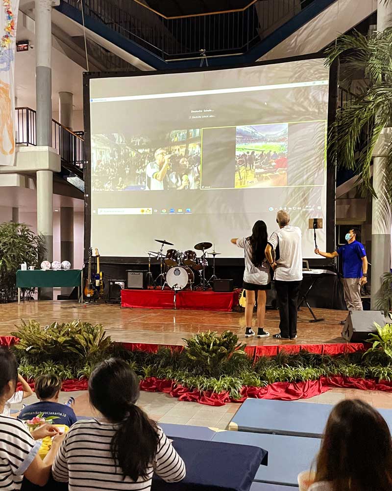 A group of people are watching a presentation on a large screen.