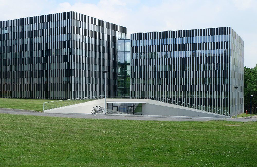A large building with a lot of windows is sitting on top of a lush green field.