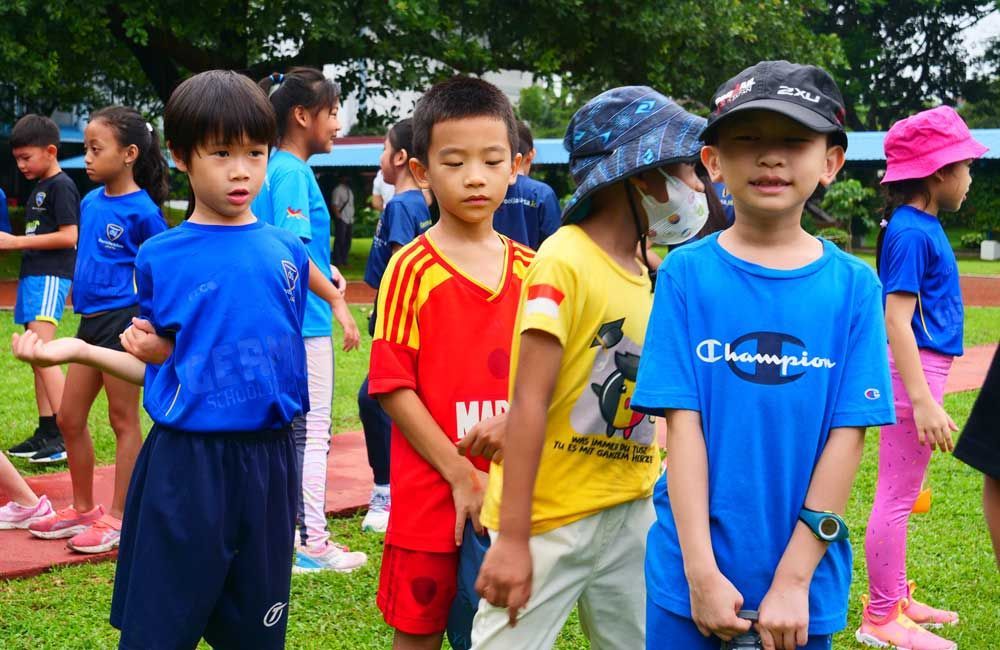 A group of children are standing in a line on a field.