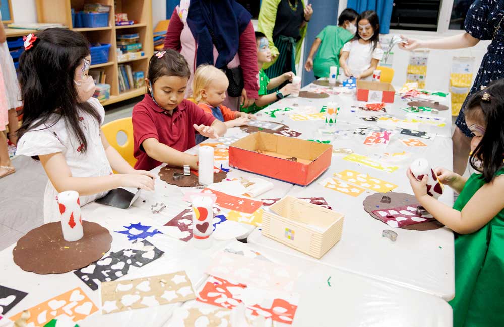 A group of children are sitting at a table making crafts.