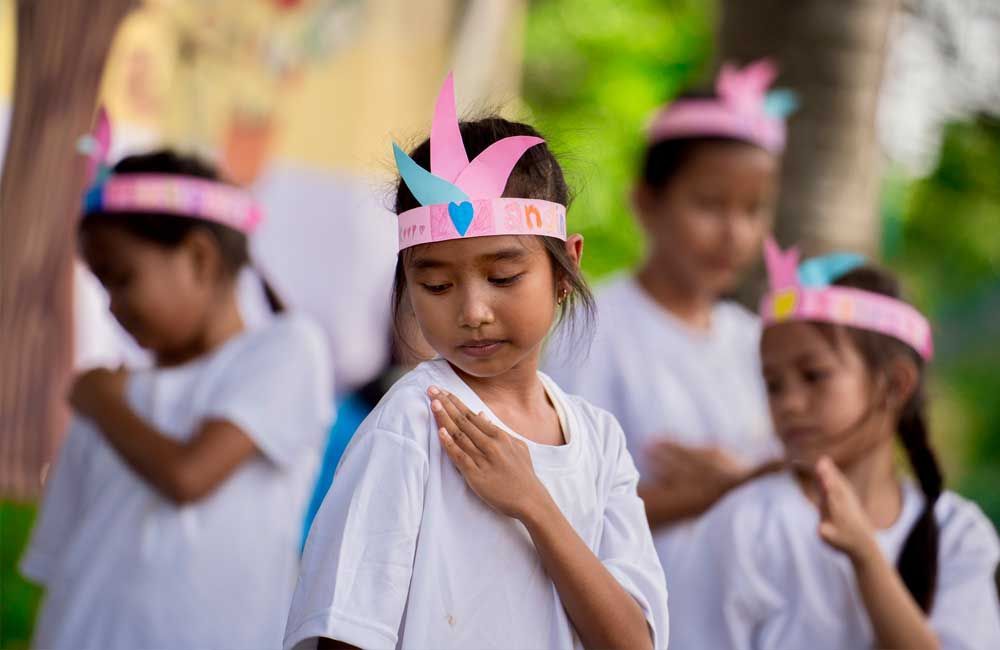 A group of young girls wearing paper hats are standing in a line.