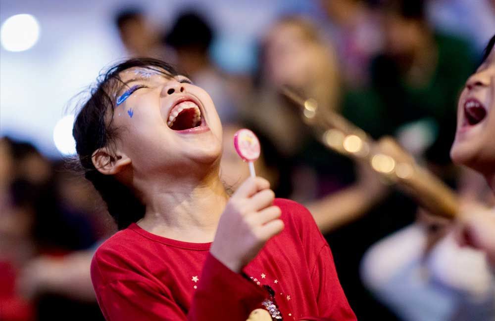A little girl is holding a lollipop in her hand and laughing.