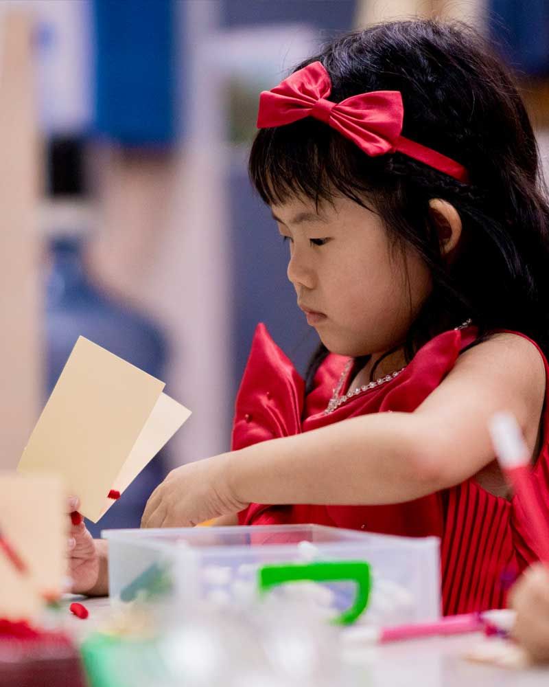 A little girl in a red dress with a red bow on her head