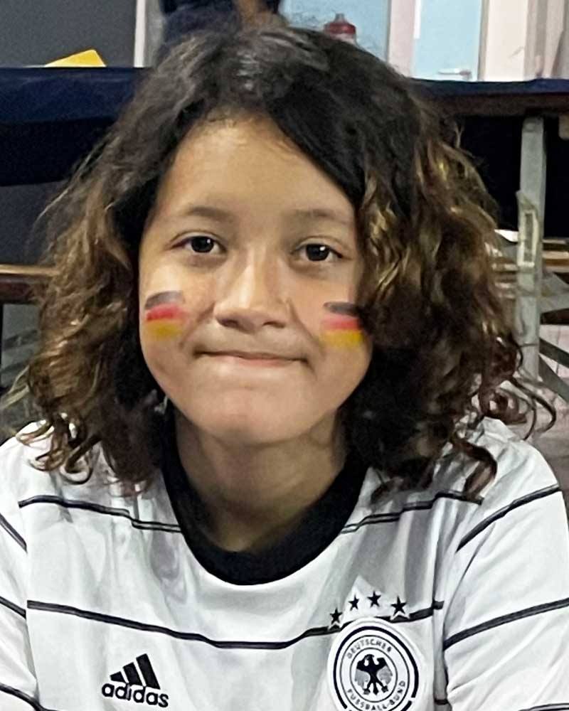 A young girl with a german flag painted on her face is wearing an adidas shirt.