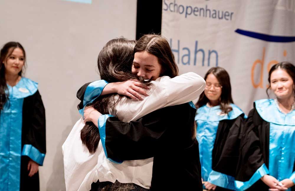 A woman is hugging another woman at a graduation ceremony.