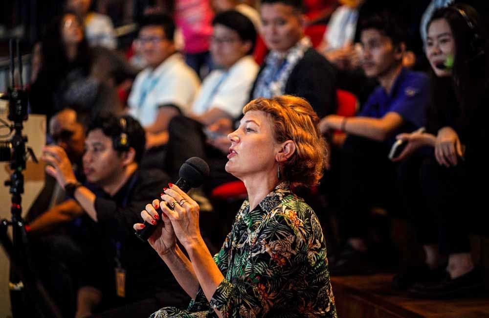 A woman is holding a microphone in front of a crowd of people.